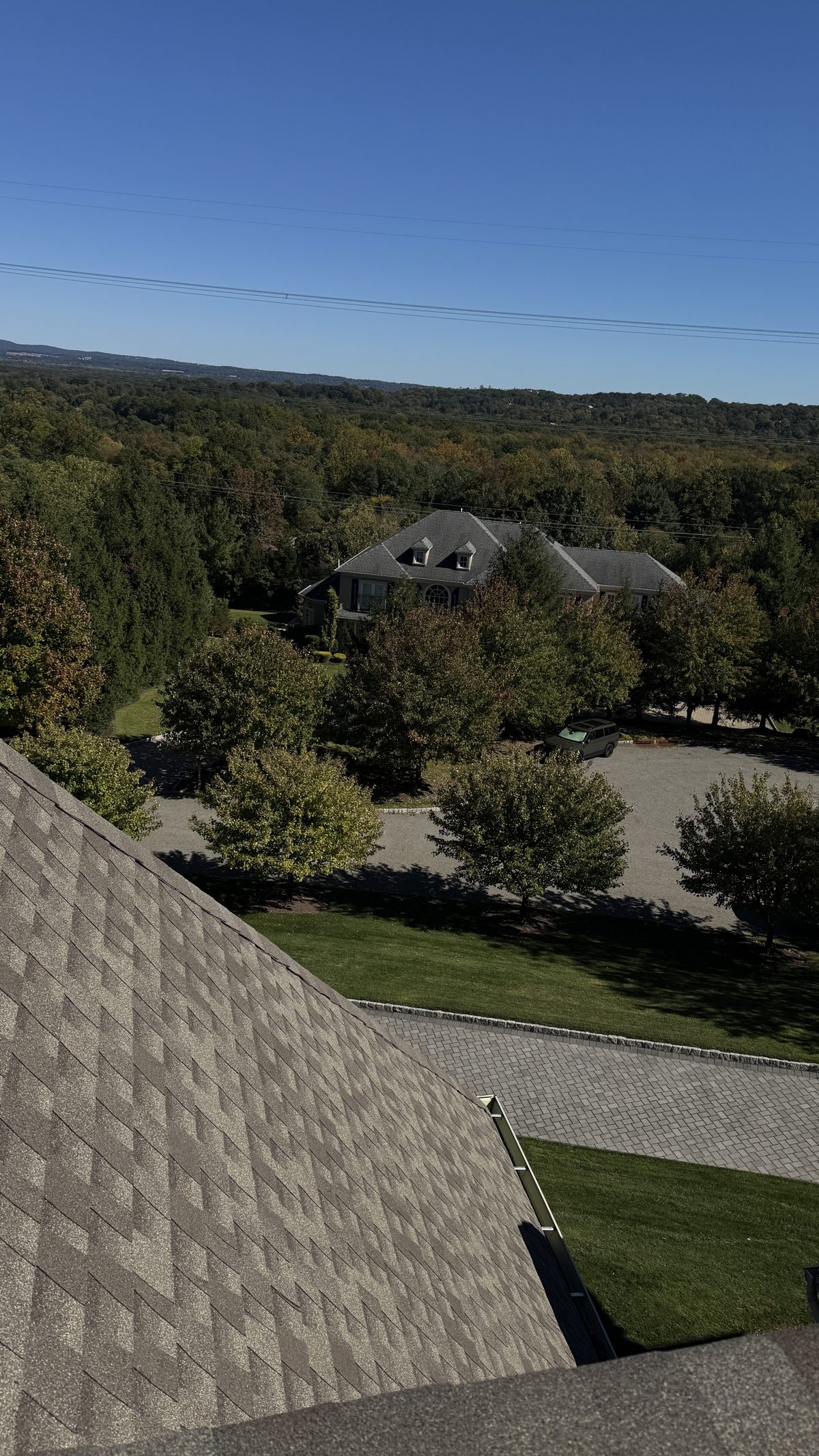 Newly finished shingle roof edge and clean gutter over a paver driveway in East Hanover, NJ