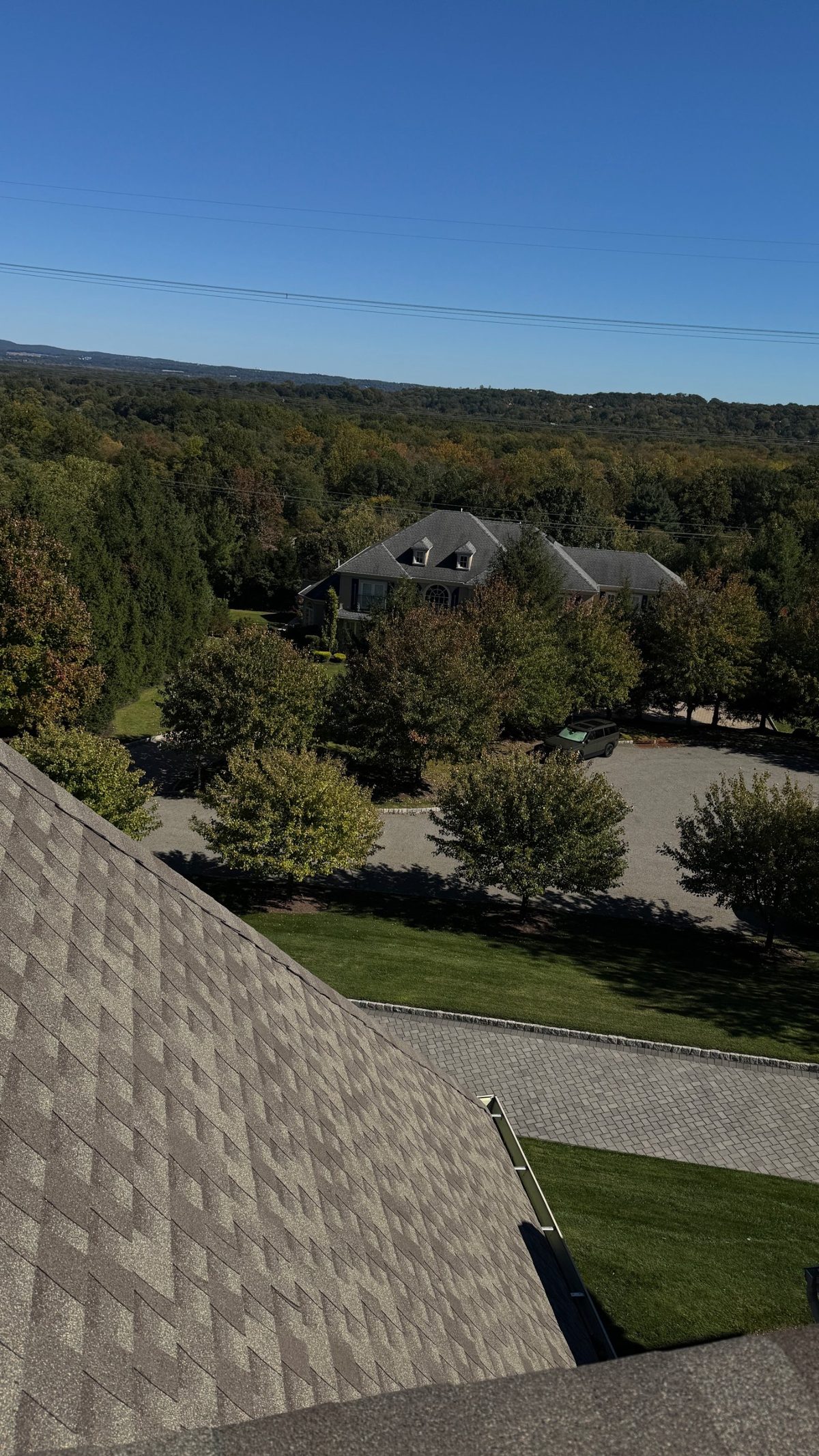 Finished architectural shingle roof with a new gutter on a Parsippany, NJ home, looking out over wooded hills and a neighboring house