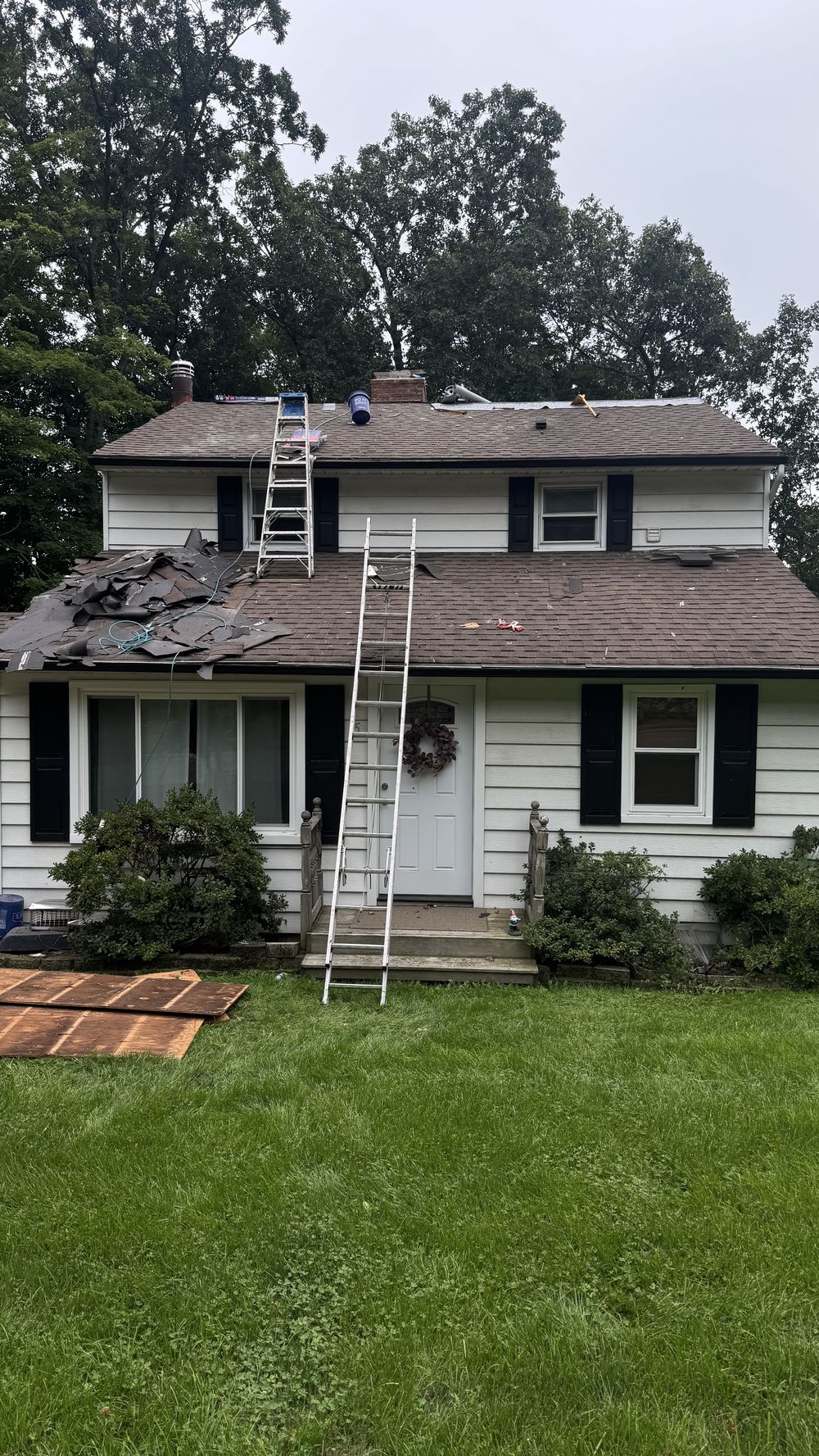 Tear-off in progress on a North Jersey home, exposing the roof deck and chimney where a long-running leak damaged the sheathing