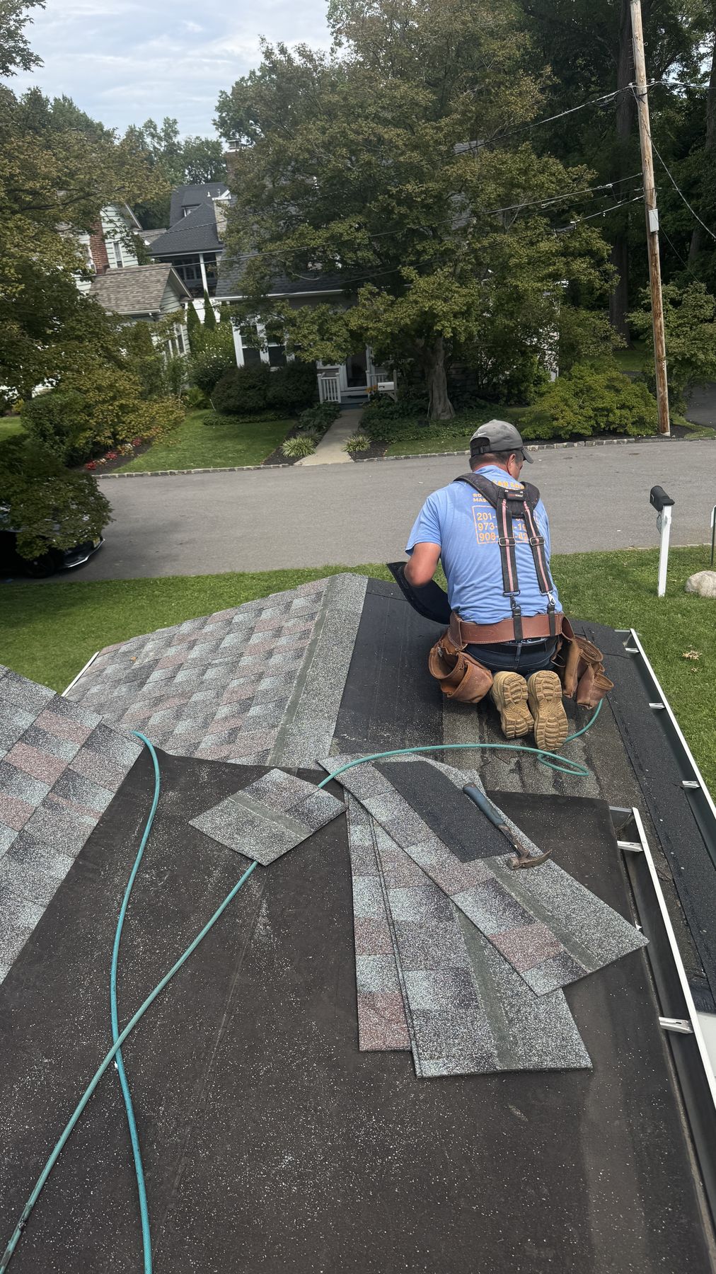 Roofer installing new architectural shingles during a storm damage roof replacement in North Jersey
